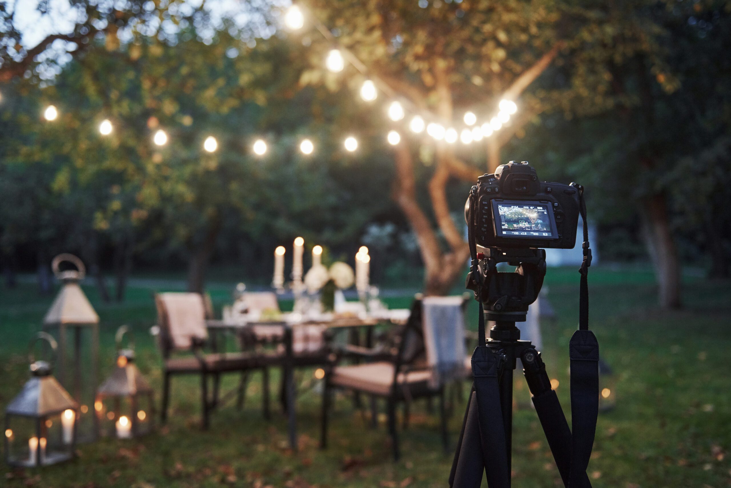Camera filming outdoor dining scene with lights.