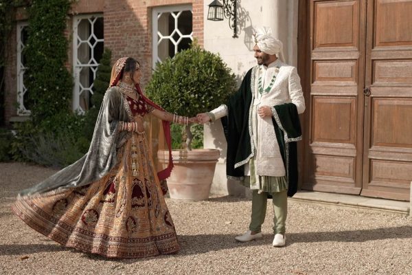 A couple in historical costumes holding hands outside a building.