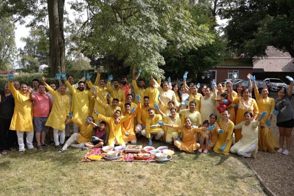 Group of people in yellow clothes celebrating outdoors with decorated plates.