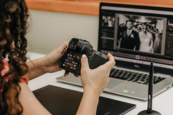 Person reviewing photos on camera and laptop.